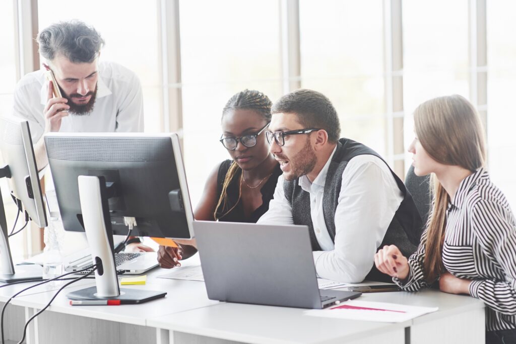 Tense work of four employees sitting in the front of monitors in the office room